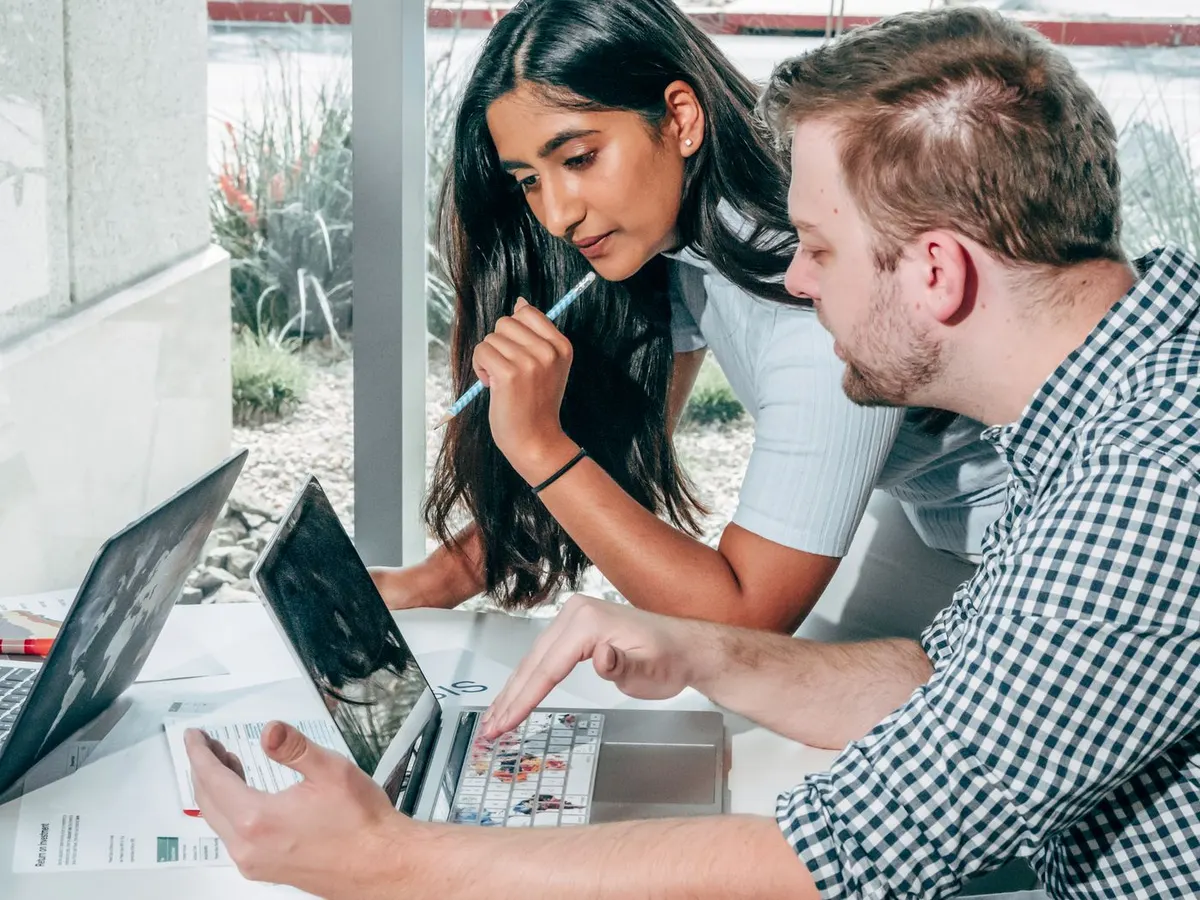 Twee mensen overleggen bij hun laptops